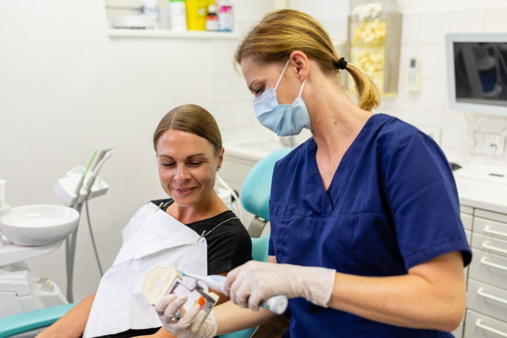 Zahnärztin erklärt Patientin anhand einer Prothese die korrekte Putztechnik